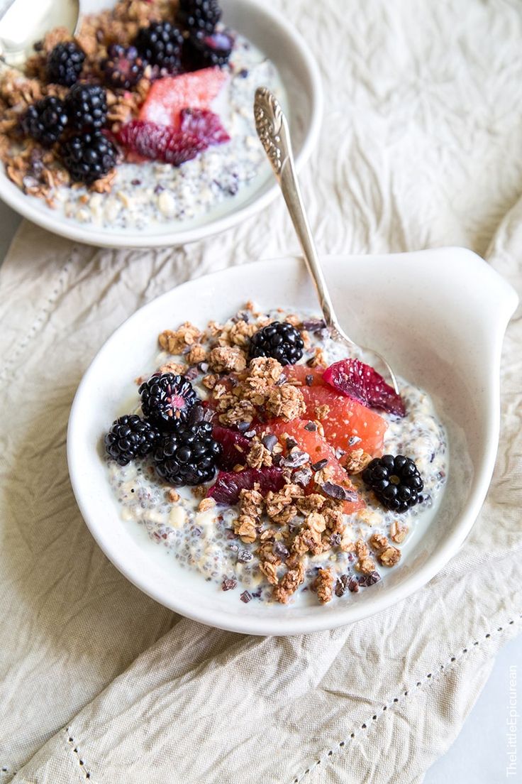 two bowls filled with oatmeal and fruit on top of a white cloth