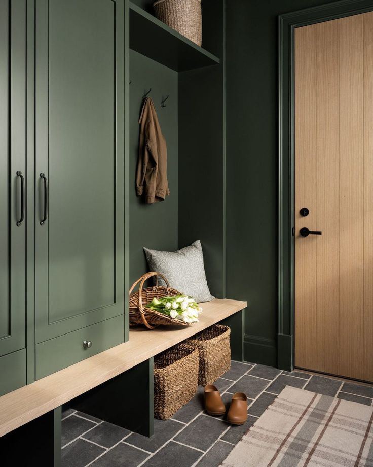 a wooden bench sitting in front of a green wall next to a brown coat rack