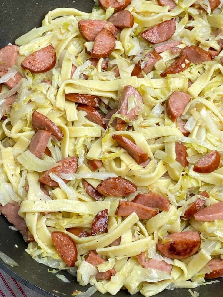 a pan filled with pasta and sausage on top of a stove