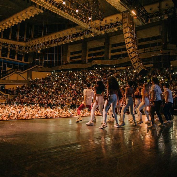 a group of people standing on top of a stage in front of a large crowd