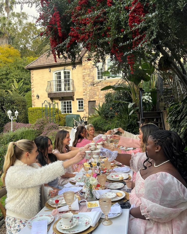 a group of women sitting at a table with plates and cups in front of them