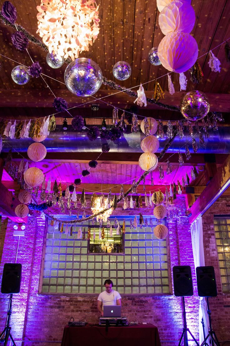 a dj is standing in front of some disco balls and other decorations hanging from the ceiling