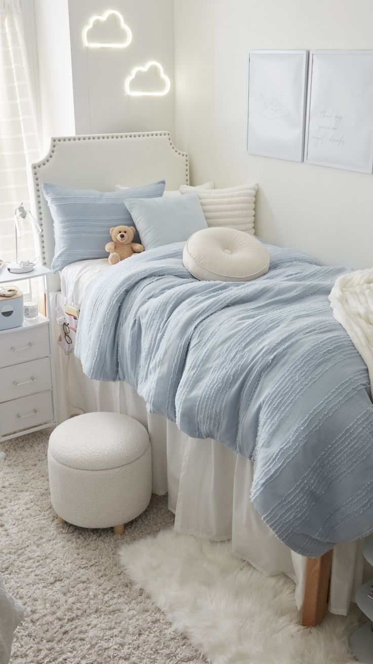 a white and blue bedroom with a teddy bear on the bed