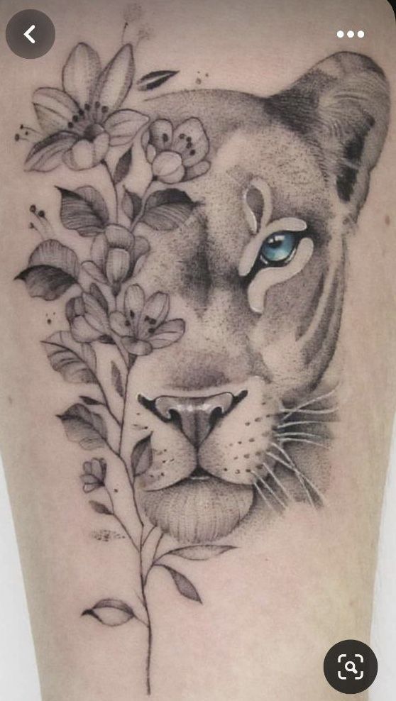 a black and white photo of a tiger's face with flowers around it on the leg