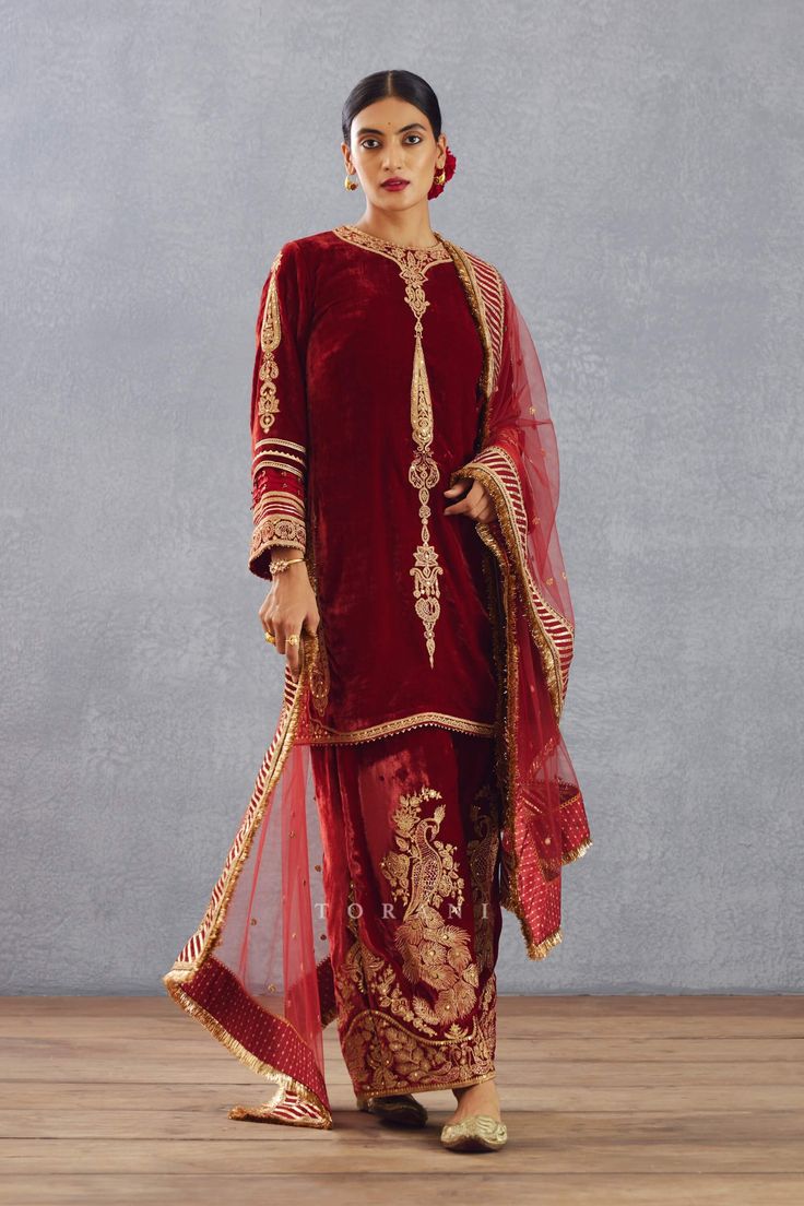 Editor's Note Featuring a bright red hand embroidered phiran set in silk velvet and embroidered sheer dupatta having sequin worked border Color: Red Fabric: Silk organza, silk velvet, cotton voile Components: Kurta, pant and dupatta Embroidery details: Hand embroidery, dori and hand adda work Fit: Loose Occasion: Wedding Guest Care: Dry Clean Only About the Designer Torani by Karan Torani stands handcrafted luxury inspired by the myriad tales of Indian mythology. Torani is a potpourri of all thi Red Kurta, Peacock Pattern, Indian Textiles, Organza Dupatta, Silk Organza, Fabric Silk, Red Silk, Cotton Voile, Silk Velvet