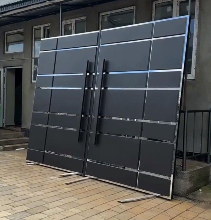 two large black gates on the side of a building