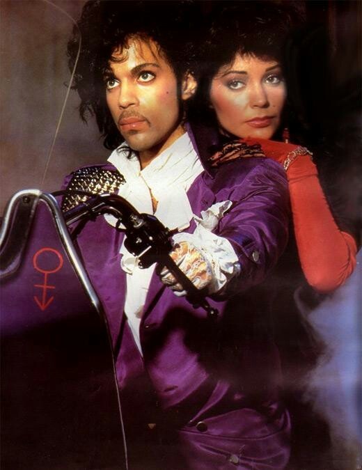 michael jackson and his wife are posing for a photo in their purple outfits, holding onto the handlebars of a motorcycle