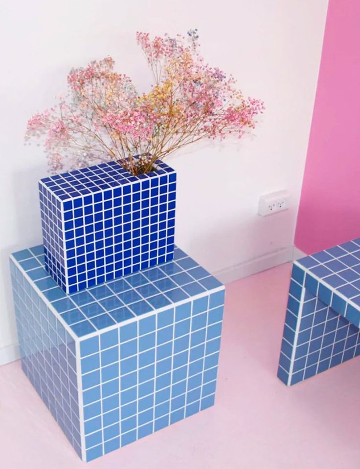 three blue boxes with flowers in them sitting on the floor next to a pink wall