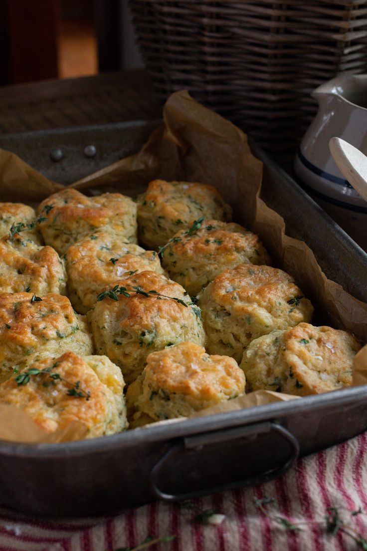 a casserole dish filled with biscuits and garnished with herbs on a table