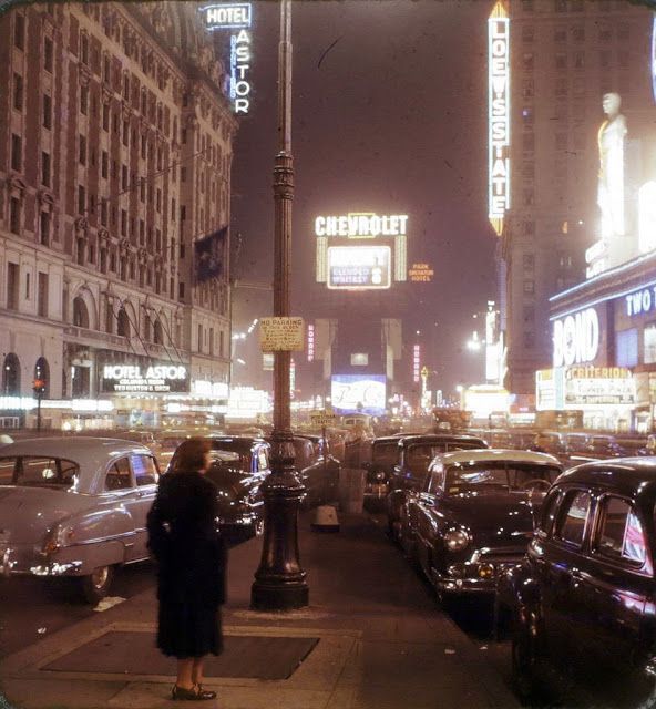 a busy city street at night with lots of cars parked on the side of it