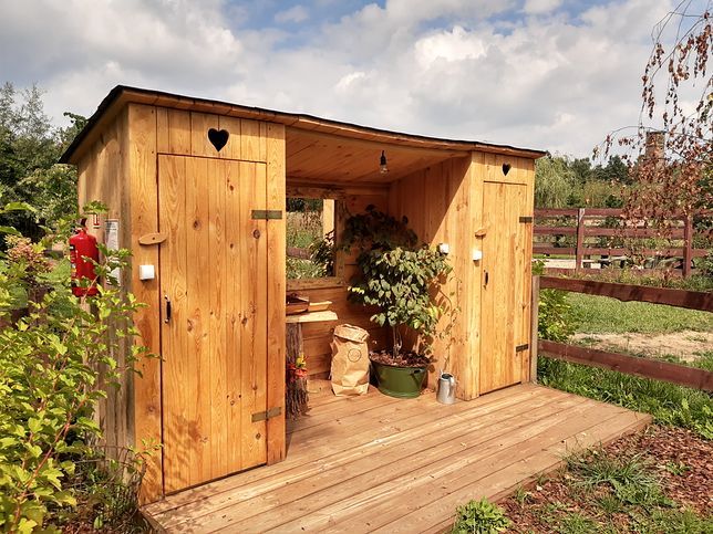 a wooden shed with potted plants in it