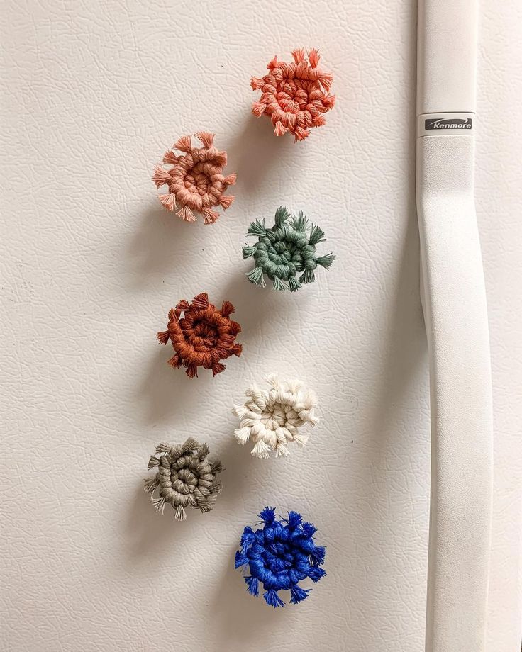 four crocheted flowers are placed next to a toothbrush on a white surface