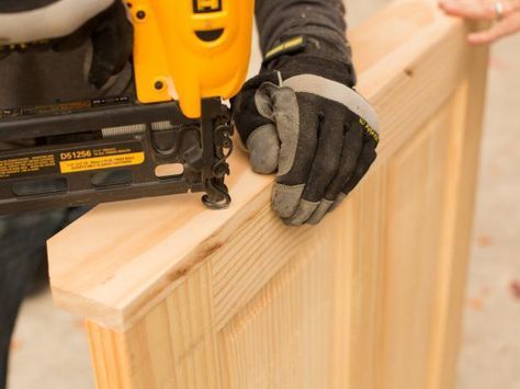 a person holding a power tool on top of a piece of wood with one hand