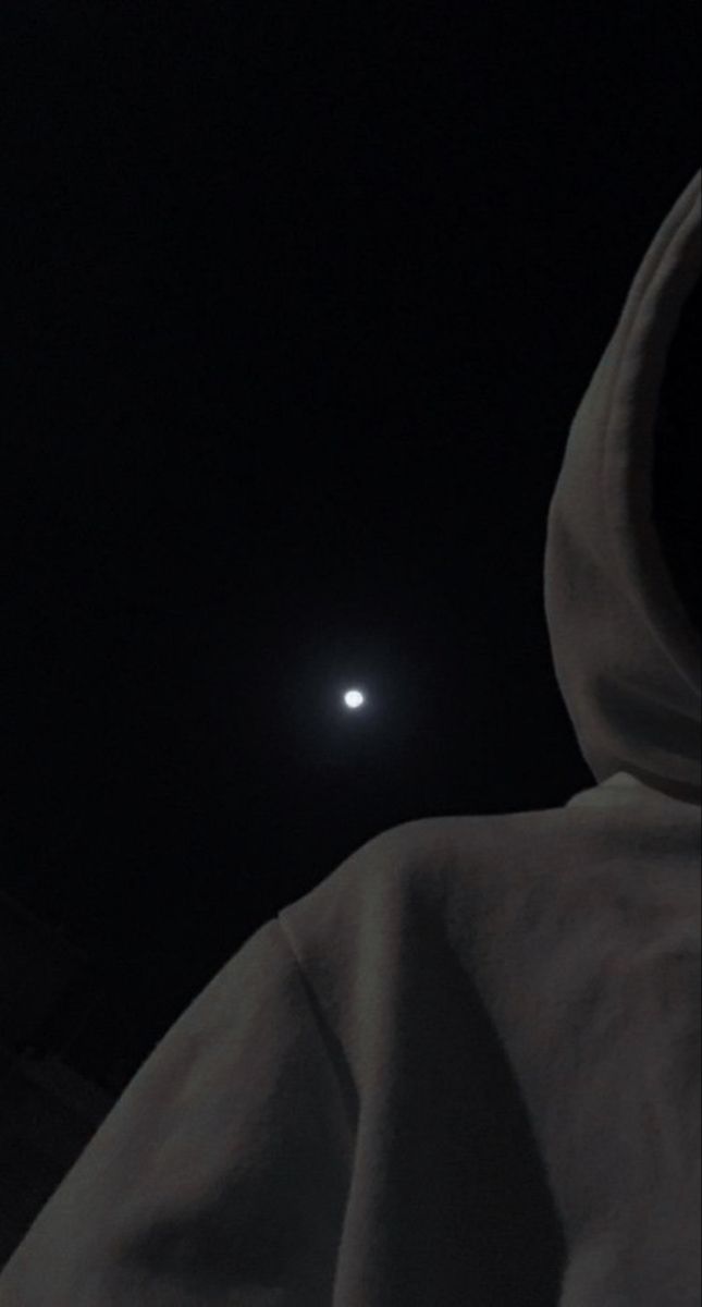 the moon is visible in the dark sky above a hooded sweatshirt on a person's head