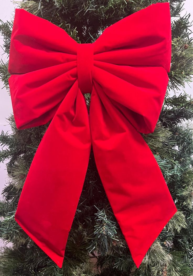 a large red bow hanging from the side of a christmas tree