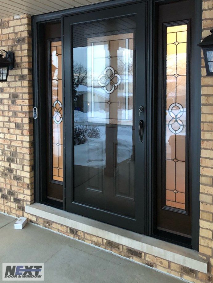 a black double door with two sidelights on the front of a brick building next to a lamp post