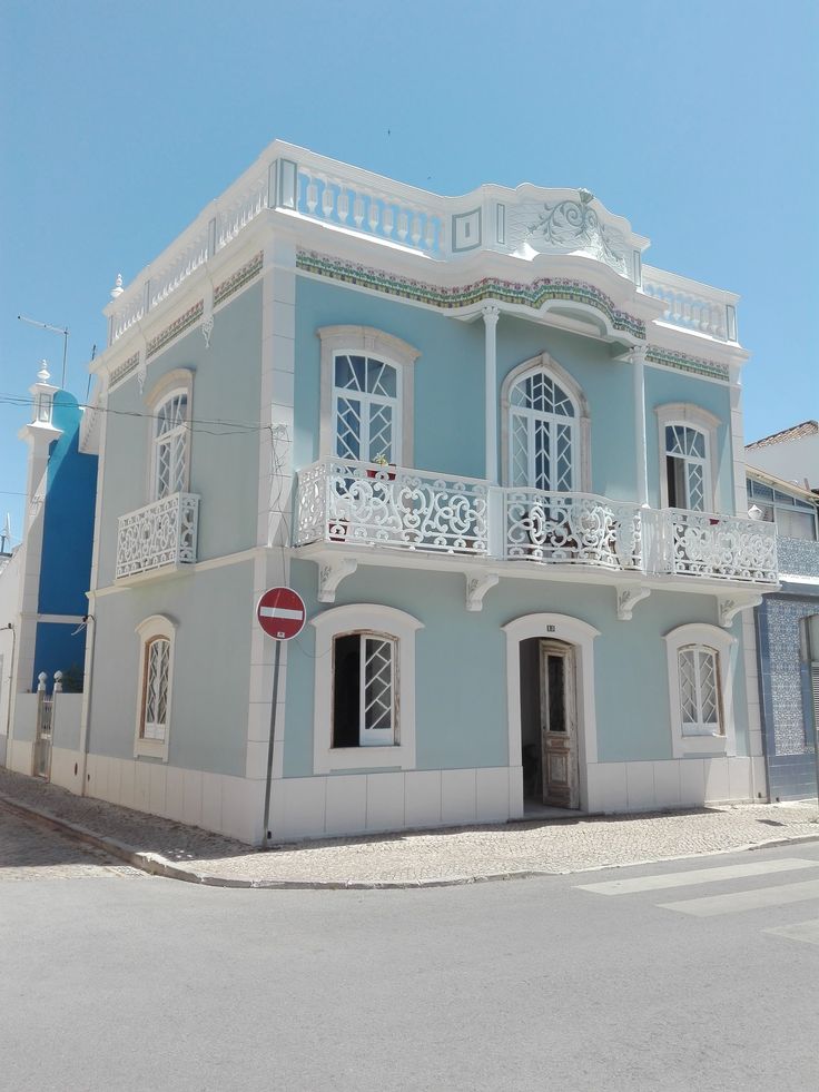 a blue and white building with balconies on the top floor is next to a street sign