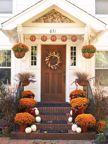 the front door is decorated with pumpkins and flowers