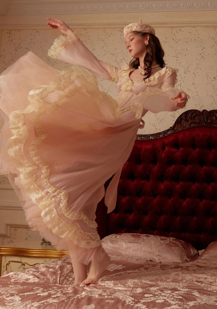 a woman in a pink dress is dancing on a bed with a red headboard