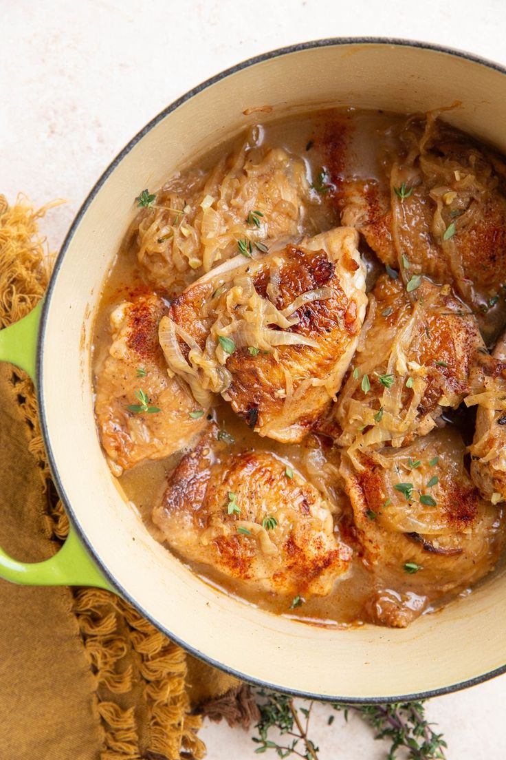 a green pot filled with meat and gravy sitting on top of a table