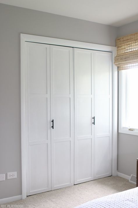 a bedroom with white closets and carpeted flooring in front of a window