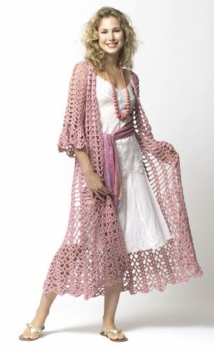 a woman wearing a pink and white crochet cover - up standing in front of a white background