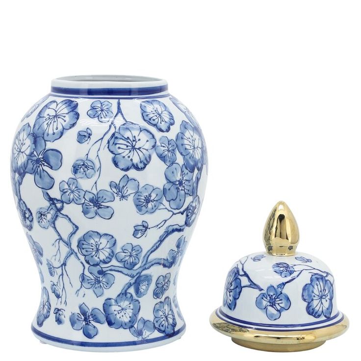 a blue and white vase next to a gold covered lid on a white background with flowers