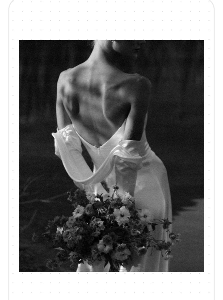 a black and white photo of a woman in a wedding dress holding a flower bouquet