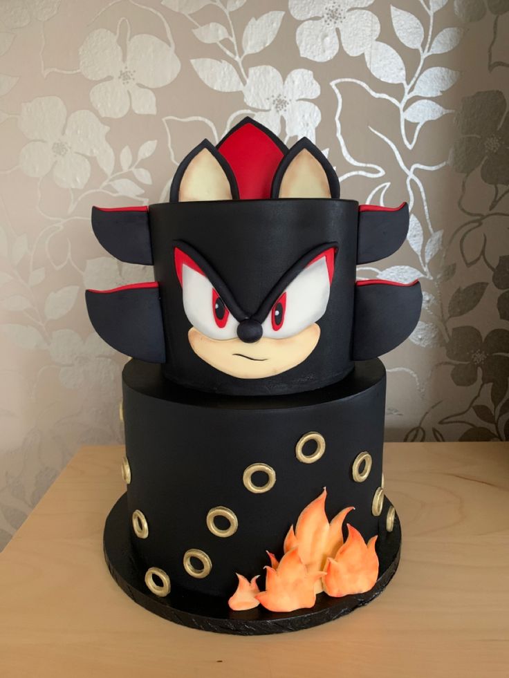 a black cake with red and white designs on it's face is sitting on a table