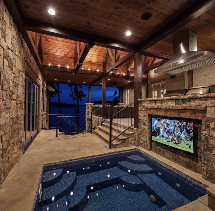 an indoor swimming pool with a large screen tv on the wall and stairs leading up to it