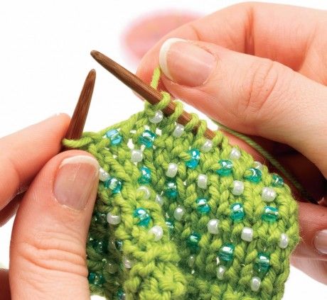 someone is crocheting something with green and white beads on it while holding a pair of scissors