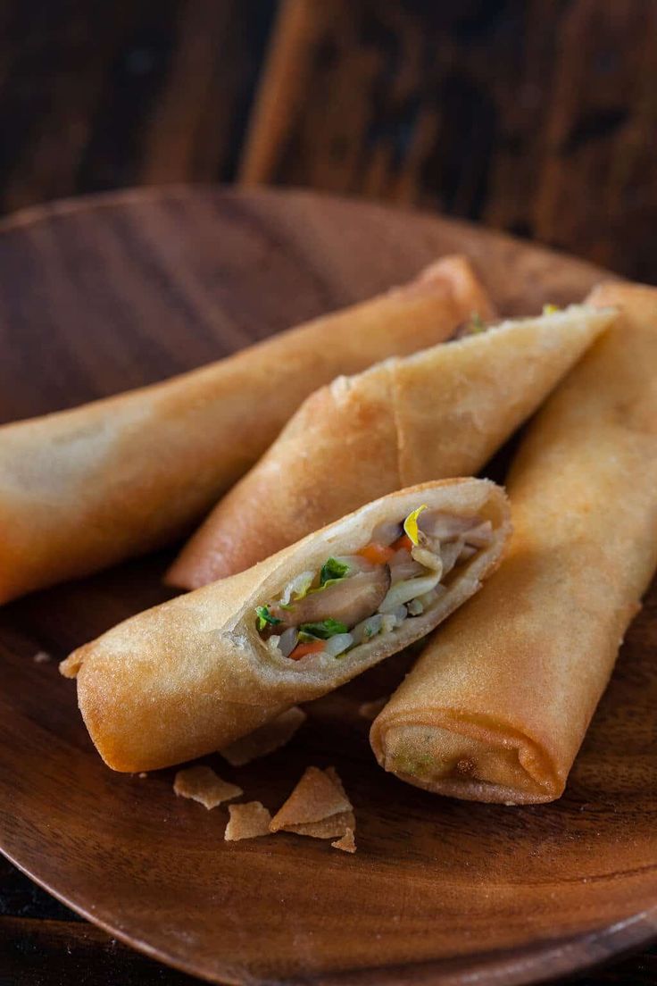 two vegetable spring rolls on a wooden plate