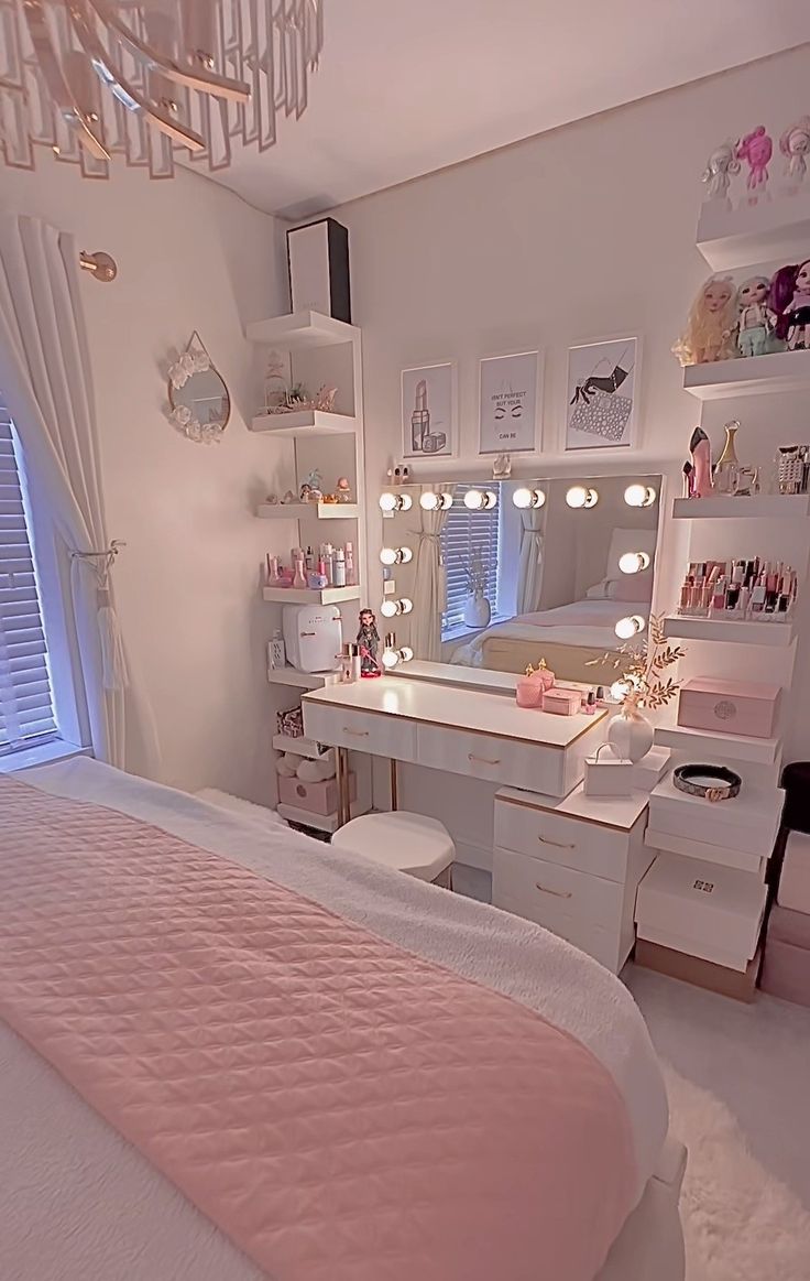 a bedroom with a bed, desk and vanity in the corner that has lights on