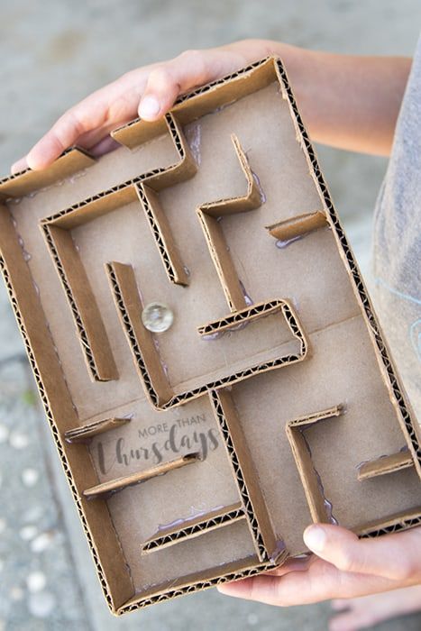 a person holding a cardboard maze in their hands