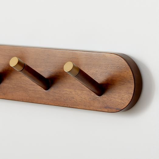 three coat hooks mounted to the side of a wooden coat rack on a white wall