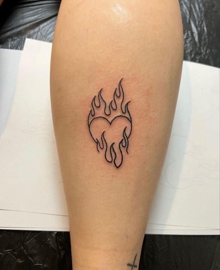 a woman's leg with a tattoo that has flames in the shape of a heart