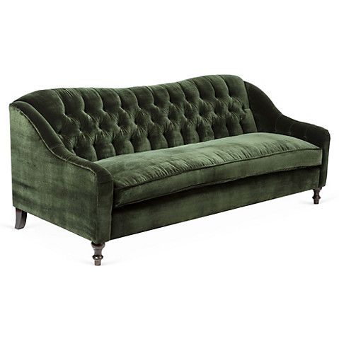 a green velvet couch sitting on top of a white floor