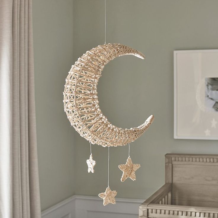 a baby's crib with a moon and stars hanging from the ceiling next to a window