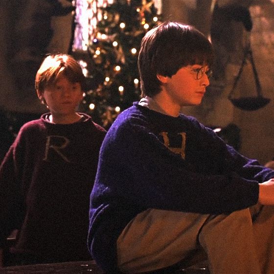 two young boys sitting next to each other in front of a christmas tree with lights