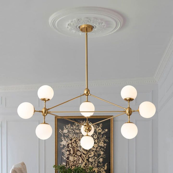 a chandelier hanging from the ceiling in a room with white walls and paintings