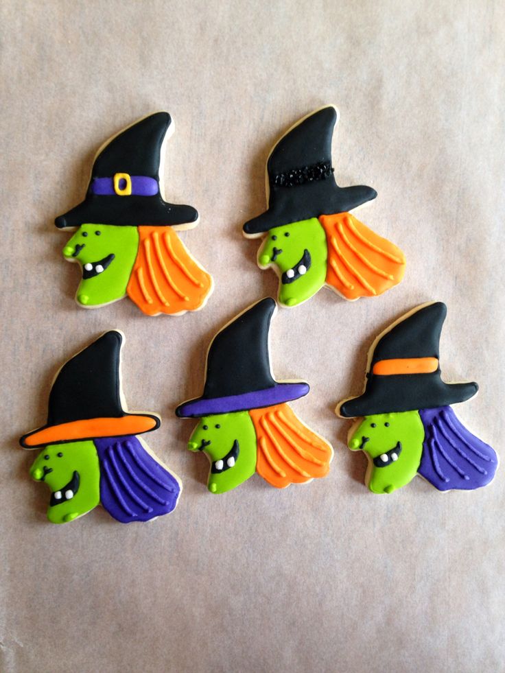 four decorated cookies in the shape of witches