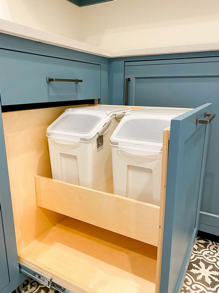 two bins are in the bottom drawer of a kitchen cabinet that is painted blue