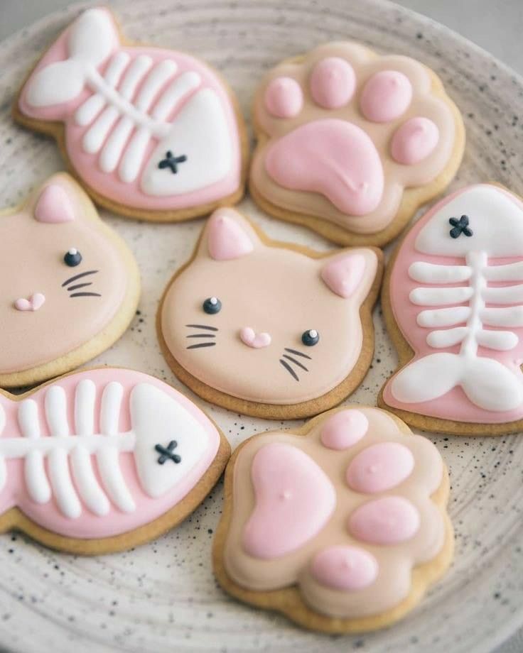 decorated cookies in the shape of cats and bones on a plate