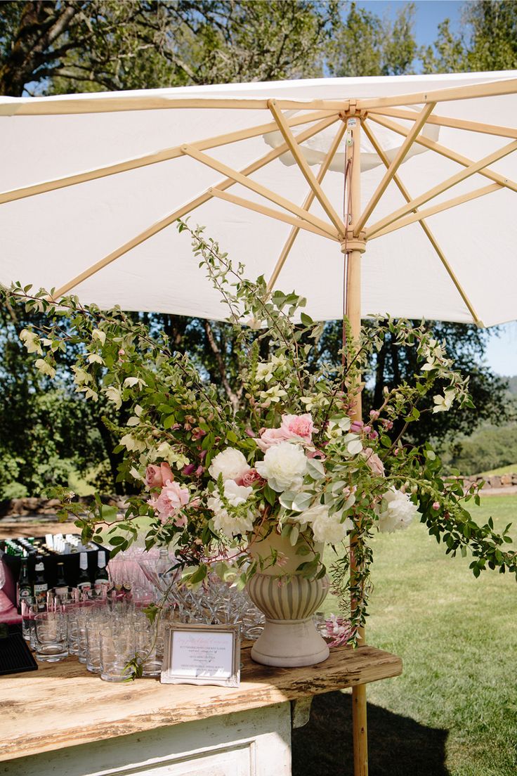 a table with flowers and wine glasses under an umbrella