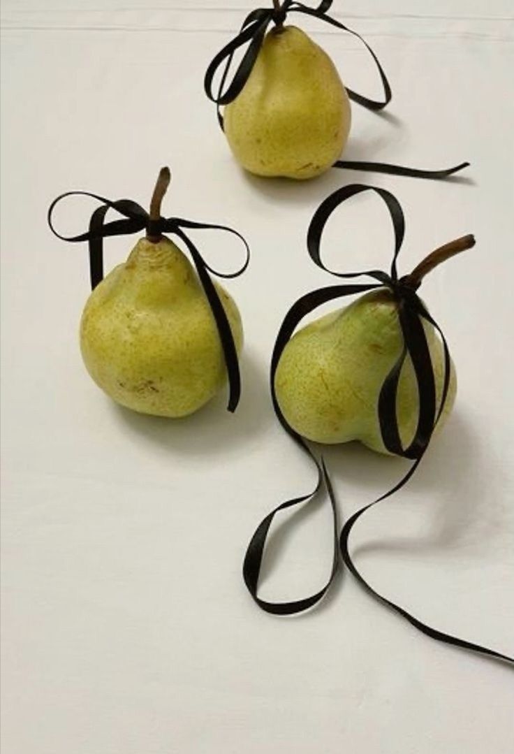 three pears tied together with black ribbon