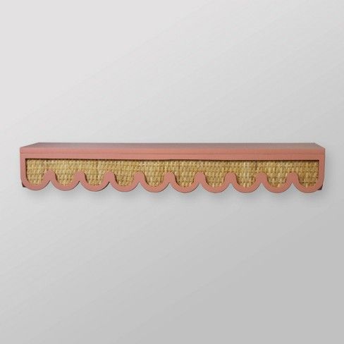 a pink and gold shelf with scalloped edges on a white wall behind it