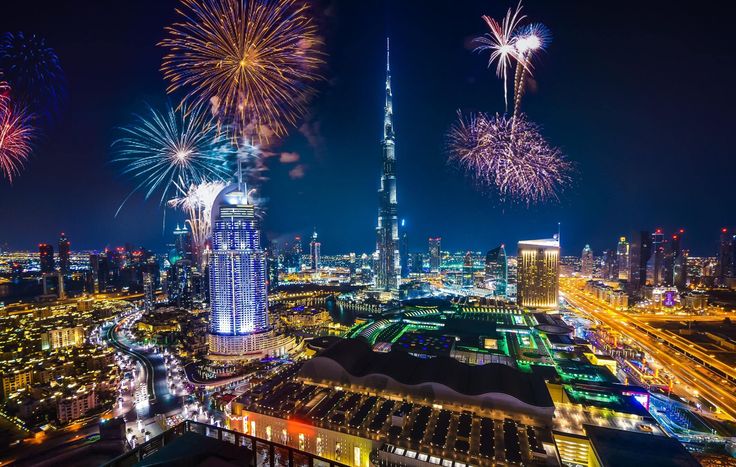 fireworks are lit up in the night sky over a cityscape and skyscrapers