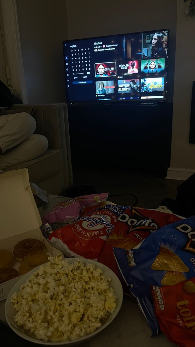 popcorn and donuts are sitting on the floor in front of a television