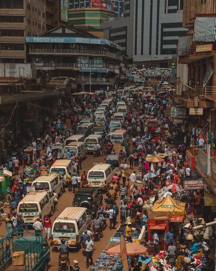 a busy city street filled with lots of traffic and people walking around it, surrounded by tall buildings