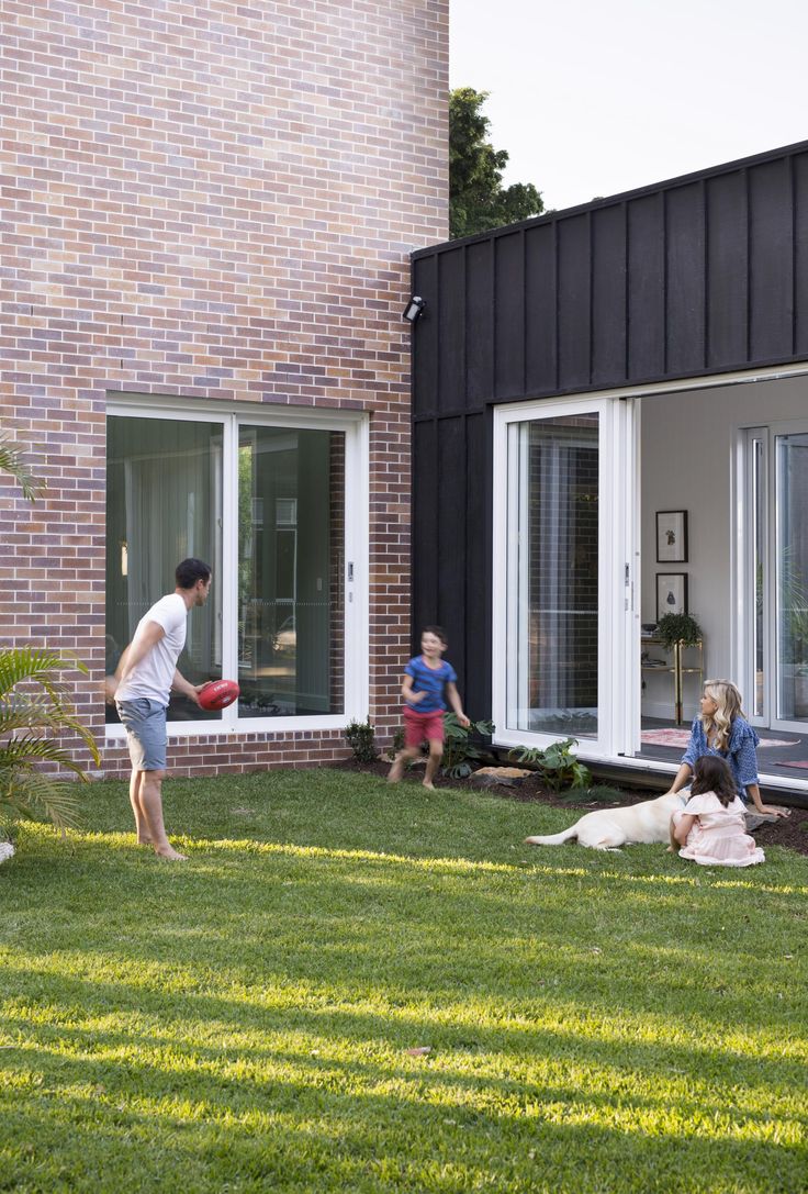 a man and two children are playing frisbee in the yard with their dog